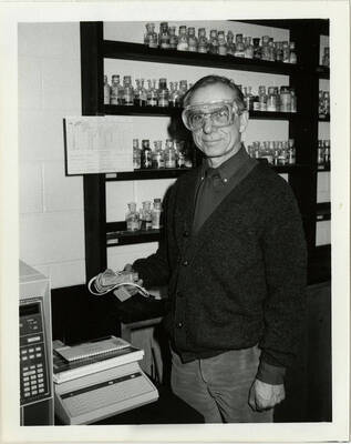 Professor James H. Cooley wearing protective goggles in a chemistry laboratory.