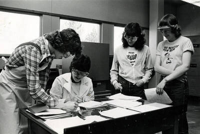 Four engineering students wearing protective eyewear working together.