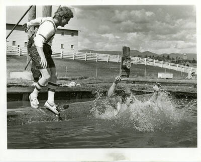 Students log rolling, one falling into water.