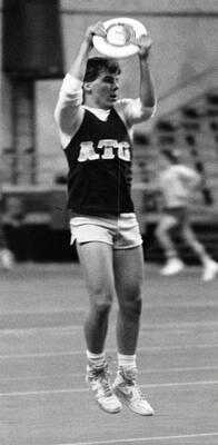 Student fraternity member (ATG) catching a frisbee.
