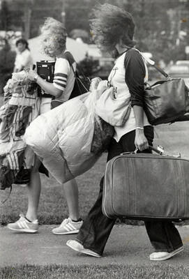 Students carrying personal items and luggage are moving into the dorms on campus.