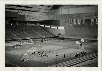 Basketball players scrimaging on multiple courts in one gymnasium.