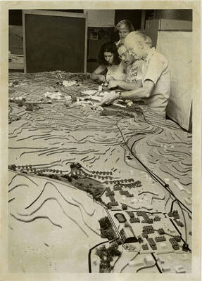 Four people work on building models out of Legos and cardboard in an Architecture class.