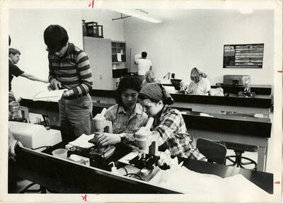Biology students participating in class activities with microscopes in a classroom.