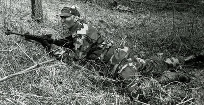 A soldier holding a rifle and wearing warpaint during training exercise.