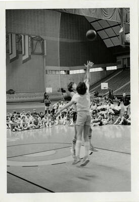 Two basketball players playing on the court, fighting for the basketball.