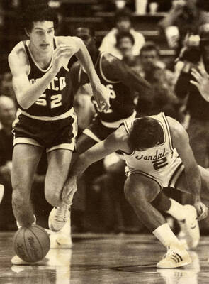 Vandals basketball player Chris Carey (21) up against Boise State University's John Martin (52).