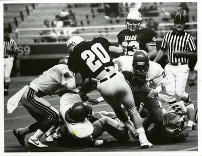 Cluster of football players surrounding the ball.