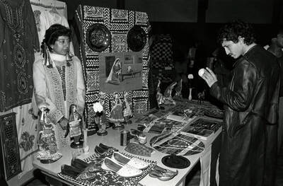 A student looks at various items on a table at an international event, possibly ""Cruise the World.""