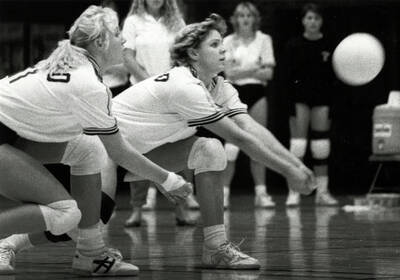 Two students playing volleyball.