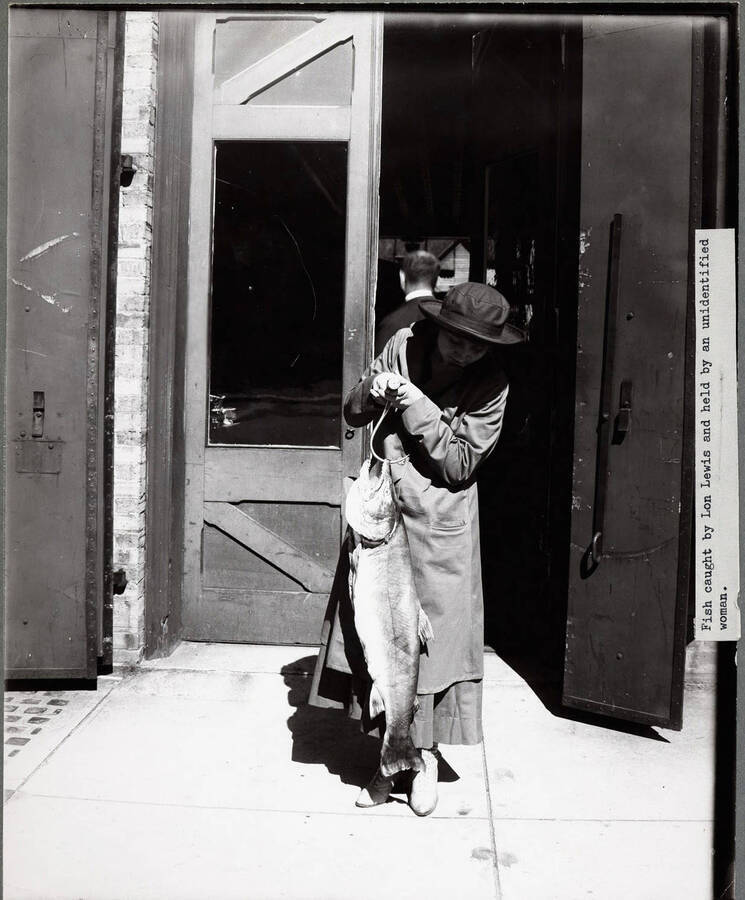 A woman holding a fish outside of Coeur d'Alene Hardware Co.