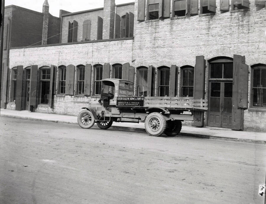Image shows a GMC truck with advertising for the Coeur d'Alene Hardware and Foundry Company in Wallace, Idaho.