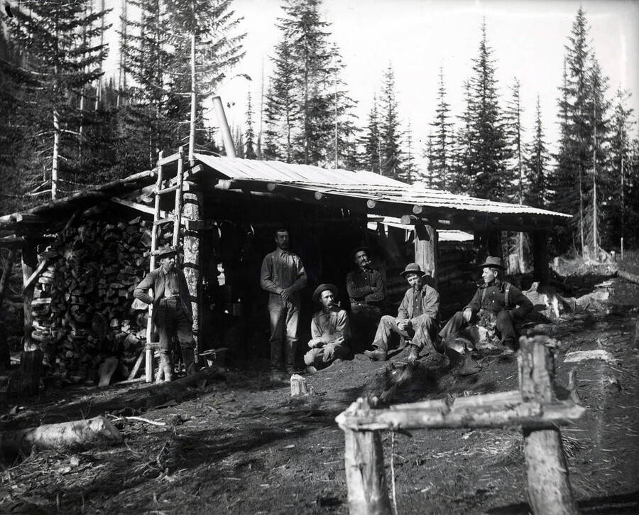 Group of men outside of a cabin.