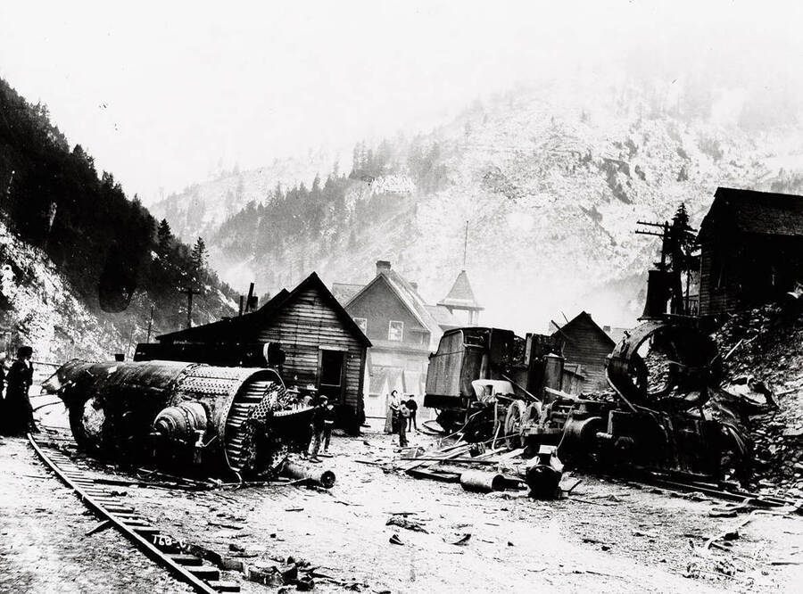 Close-up view of the Northern Pacific train engine explosion debris.  Various citizens can be seen examining the wreckage, which has come close to some of the houses.