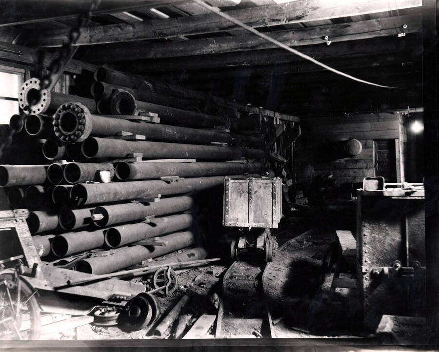 Interior of the Amazon Dixie Mine in Sildex, Montana, 1923 where pipes and an ore car on a track can be seen.