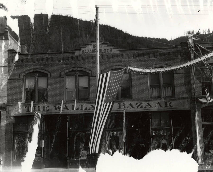 The exterior front view of the Wallace Bazaar; in Wallace, Idaho; with a flag out front.