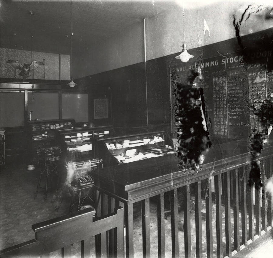 The interior view of Walter J. Bracking Real Estate and Mining Brokerage office in Wallace, Idaho. Shows off the typewriters, desks, phone, spittoon, and chart on the wall