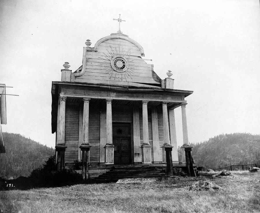 This image shows the deteriorated state of the Mission of the Sacred Heart, overlooking the Coeur d'Alene River. The Mission was constructed between 1850-1853 by Jesuit missionaries. Caption from front: Old Mission, Idaho.