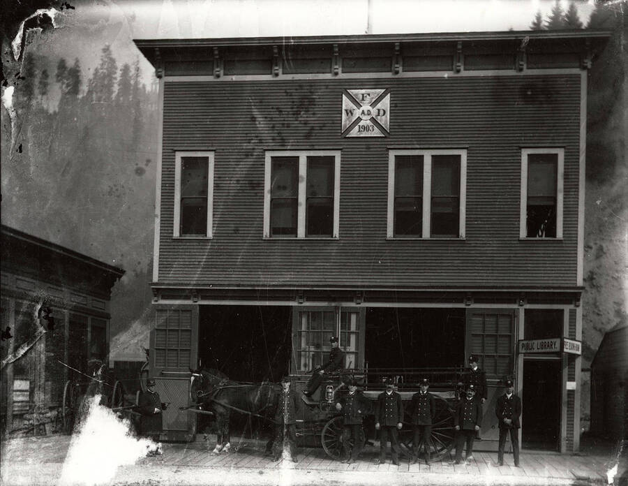Wallace Fire Department standing in front of the fire station in Wallace, Idaho. The fire station was also the public library.