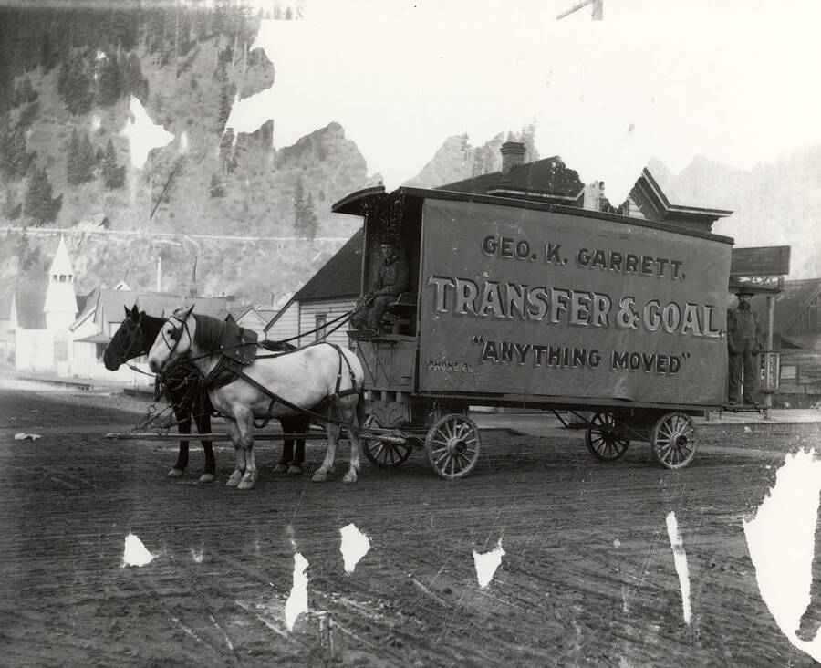 Horse drawn wagon with a large sign for George K. Garrett Transfer and Coal of Wallace, Idaho