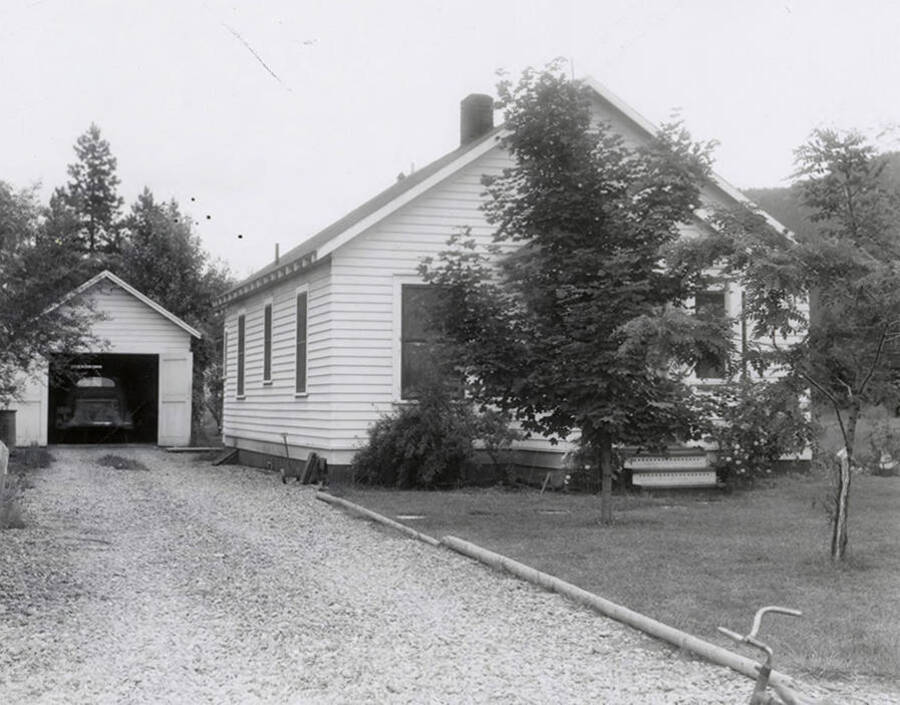 View of a house in Wallace, Idaho. A car can be seen parked in the garage. A real estate view taken for Idaho First National Bank.