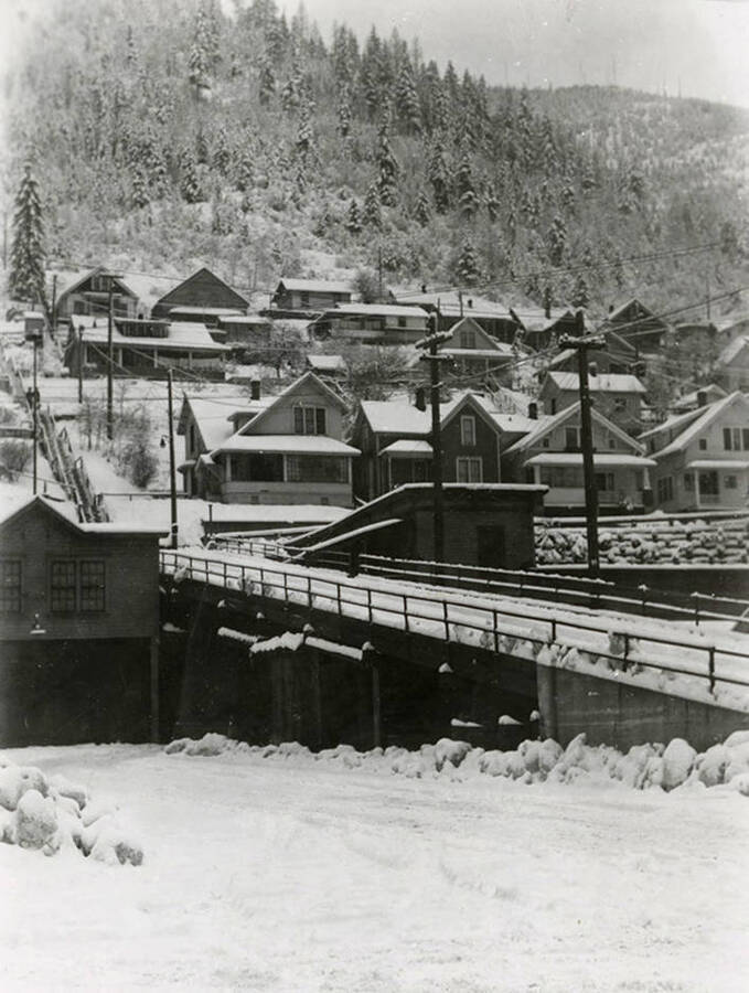 View of where Seventh Street comes onto the Viaduct in Wallace, Idaho. Houses can be seen on the other side of the bridge. Both the bridge and houses are covered in snow.