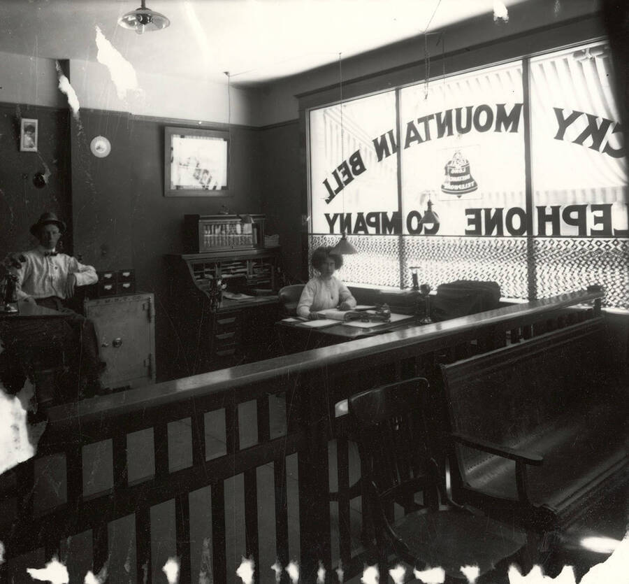 A man and woman sitting inside the Rocky Mountain Bell Telephone Company office in Wallace Idaho