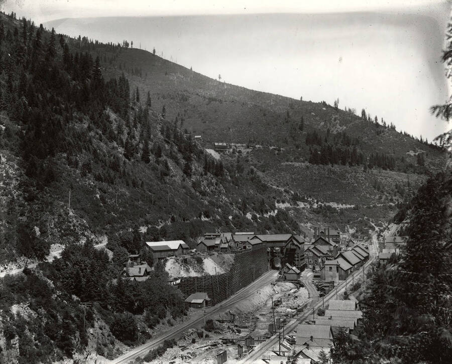 View of the mine and mill buildings, hills, and railroad tracks in Mace, Idaho.