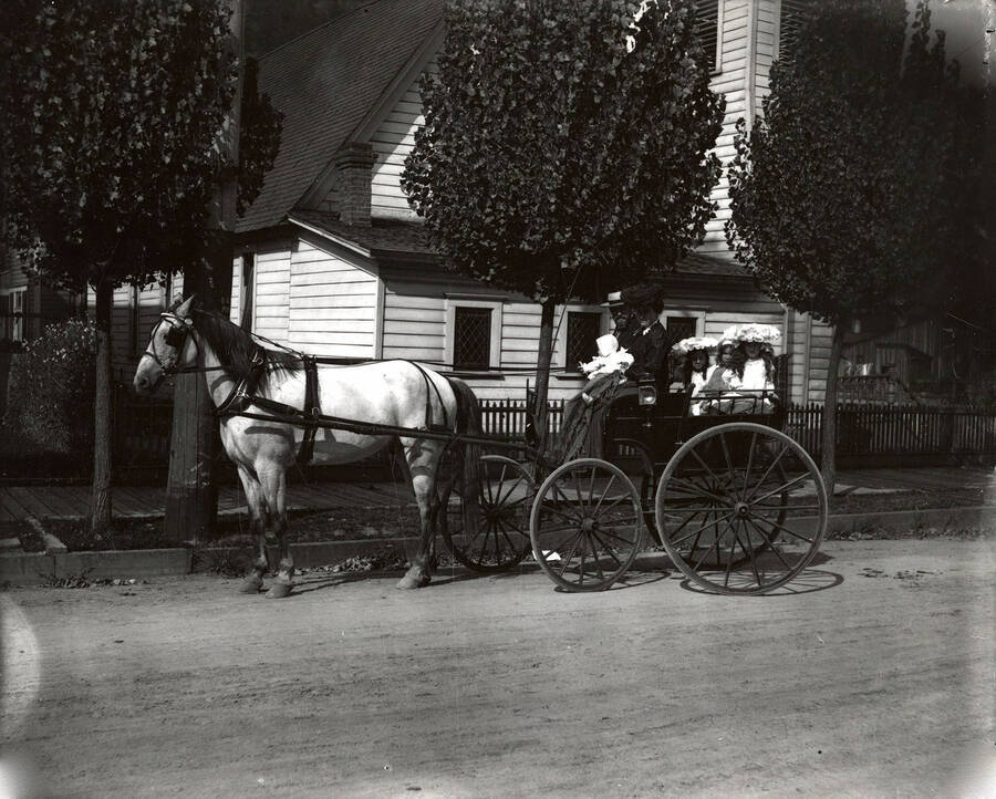 Mr. and Mrs. Walker with their three girls and baby, in a wagon pulled by a horse.