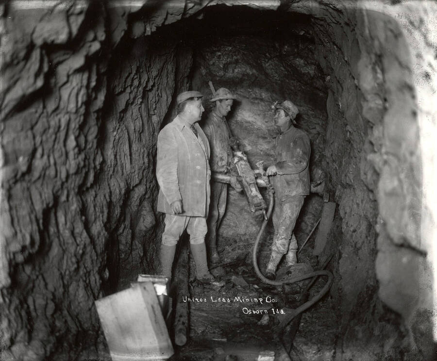 Three men with an air drill stand underground in the mine at the United Lead Mining Company in Osborn, Idaho.
