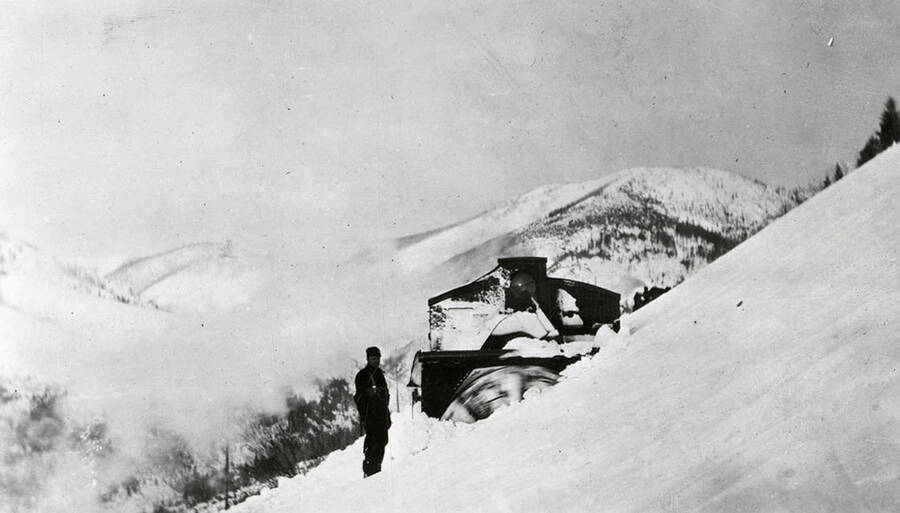 A man standing next to the rotary snow plow on the Northern Pacific Railroad.