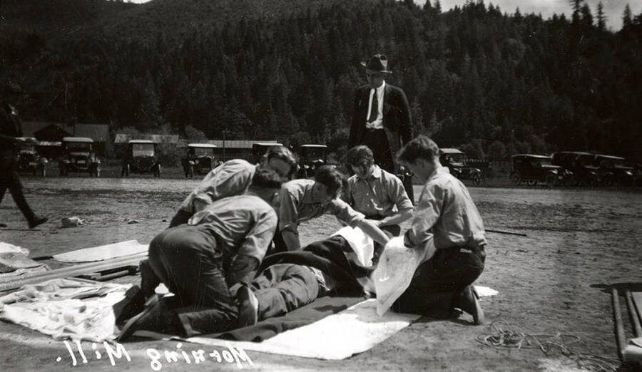 The members of Morning Mill team performing first aid at the first aid contest in Mullan, Idaho. The negative was processed backwards, hence the watermark reads backwards
