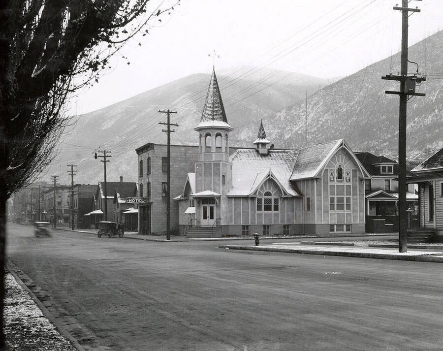 Exterior view of the Congregational Church in Wallace, Idaho. The church sits on the corner of the street, with a hotel next to it.