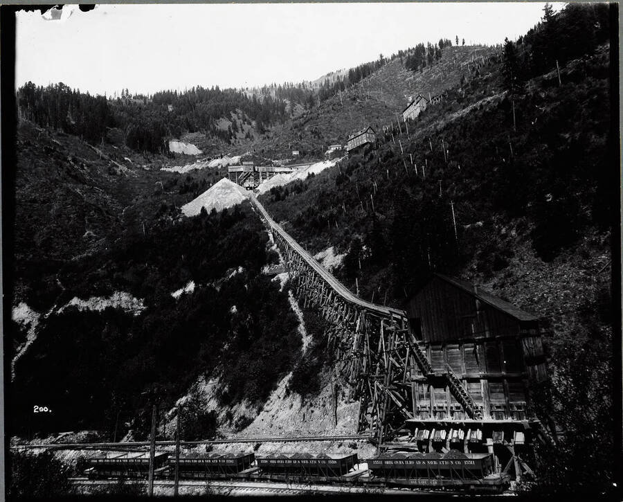 Image of the Mammoth Mine and tramway in Mace. O.W.R & N. railroad cars filled with ore can be seen at the bottom of the tramway.
