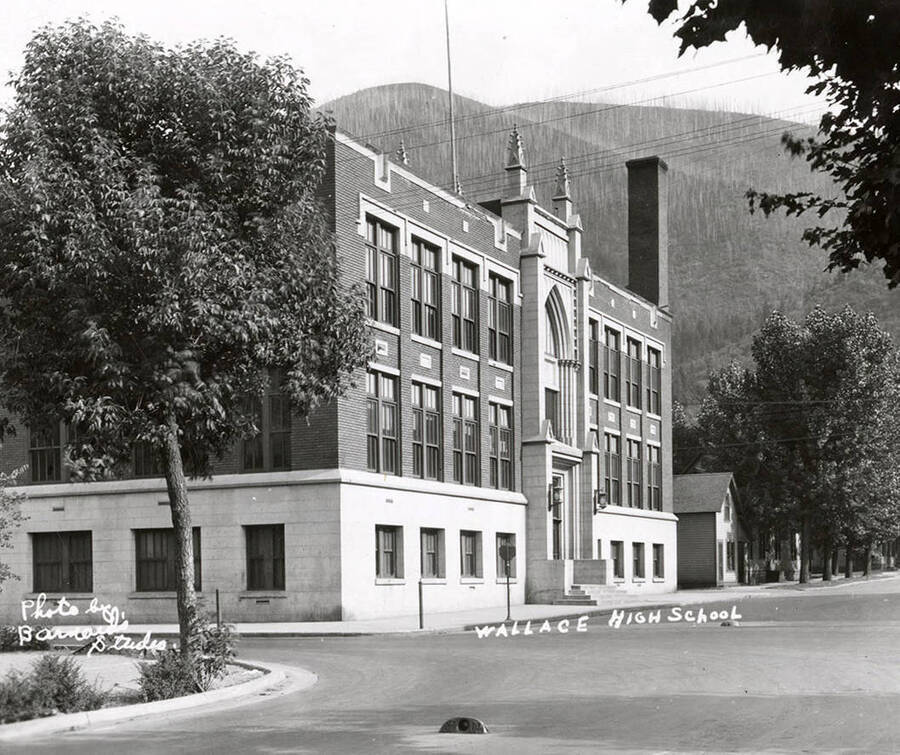 Exterior view of the high school in Wallace, Idaho. The high school sits on a street corner and has a hill behind it.