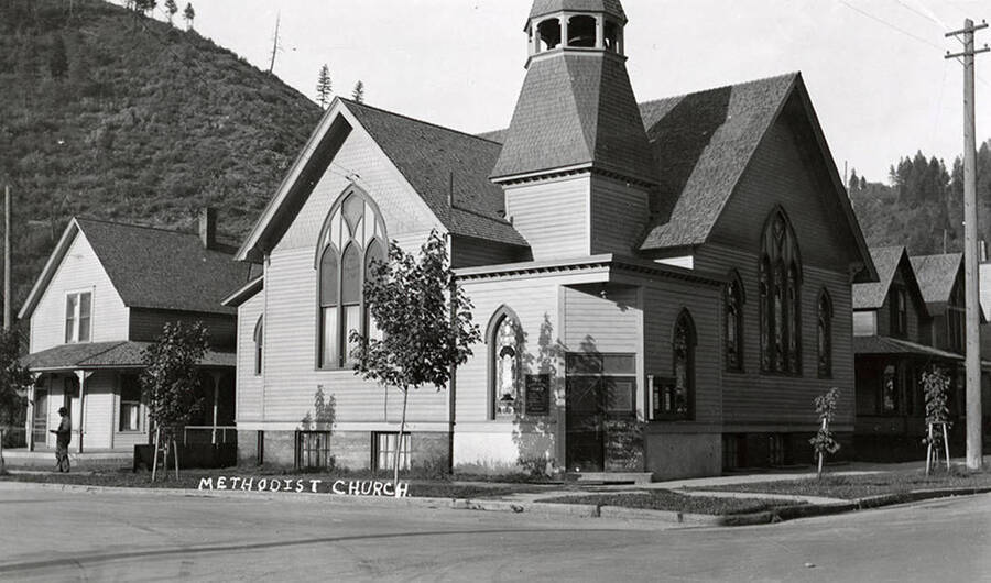 Exterior view of the First Methodist Episcopal Church in Wallace, Idaho. The church sits on a street corner, with other buildings to it's side.