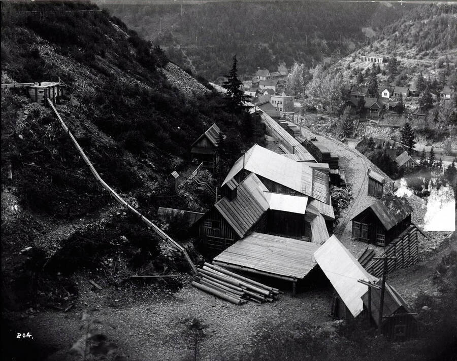 Image shows some wooden buildings on the hillside, with the town of Burke in the background. Caption on front: "Marsh Mining Co., Burke."