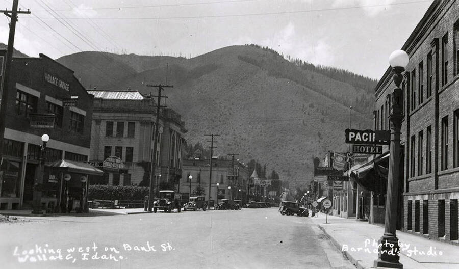 Looking west down Bank Street in Wallace, Idaho. Buildings are along the sides of the street, with cars parked out front.
