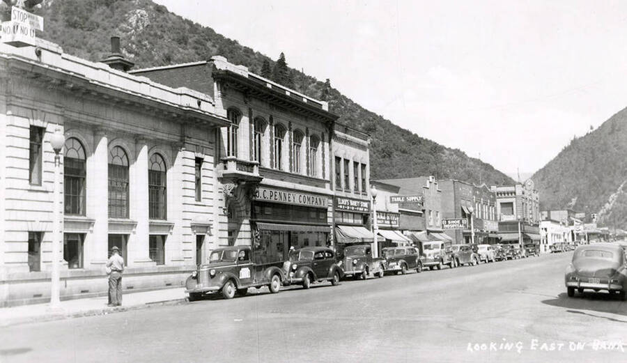 Looking down Bank Street in Wallace, Idaho. Buildings are along the sides of the street, with cars parked out front.