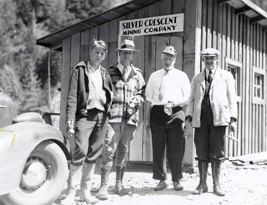 A group of men standing in front of a building with a sign that says, "Silver Crescent Mining Company," on the Silver Crescent Mine in Kellogg, Idaho.