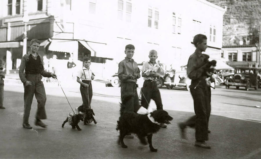 Boys walking and holding their dogs during the Veterans pet parade in Wallace, Idaho.