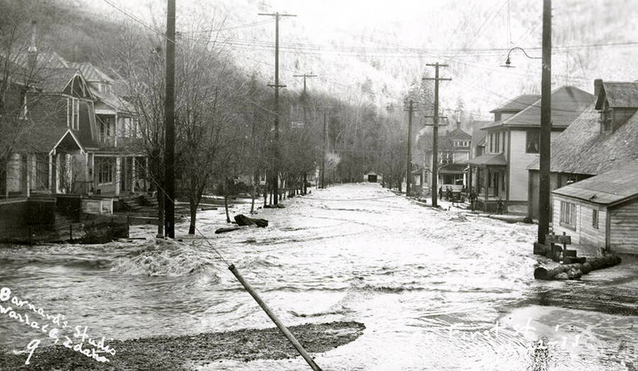 View of First Street during the Placer Creek flood in Wallace, Idaho. Houses line the street.
