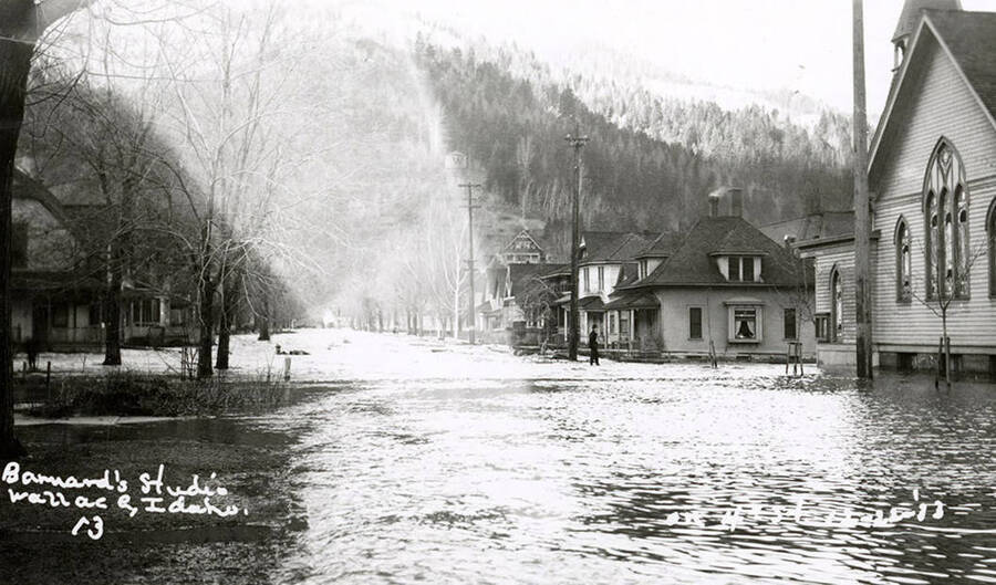 View of Fourth Street during the Placer Creek flood in Wallace, Idaho. Houses line the street.