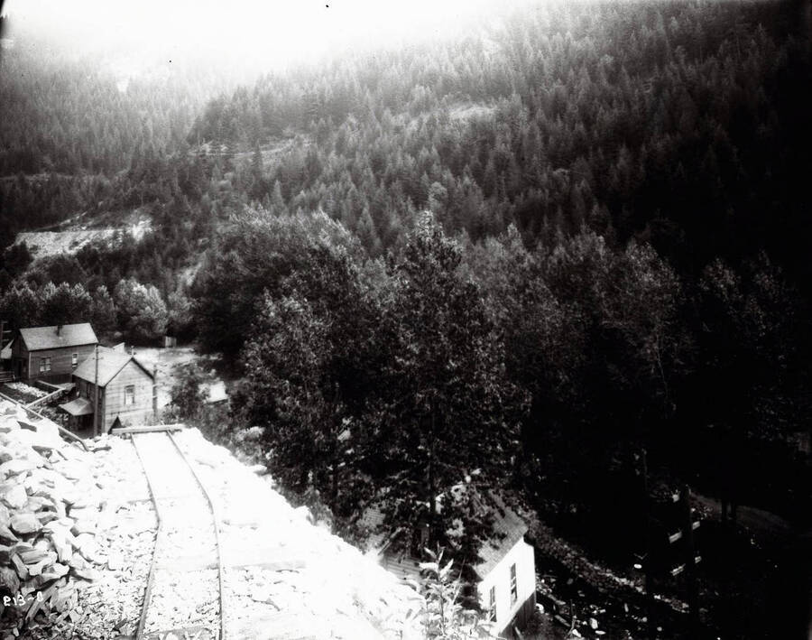 View of some mine rails and mining shacks. Caption on front: "Masser, John W. Mining property, Burke, Idaho."