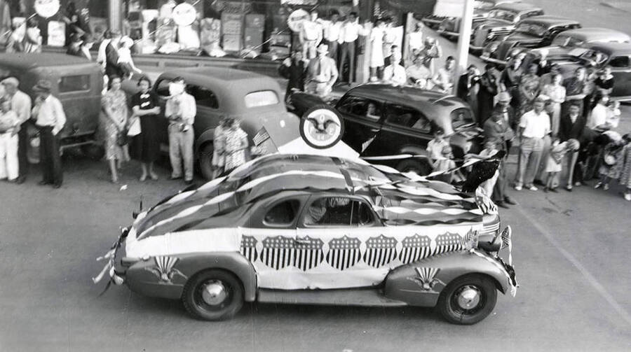 A decorated float being driven, while others stand around a watch, during the Eagles Parade in Wallace, Idaho.