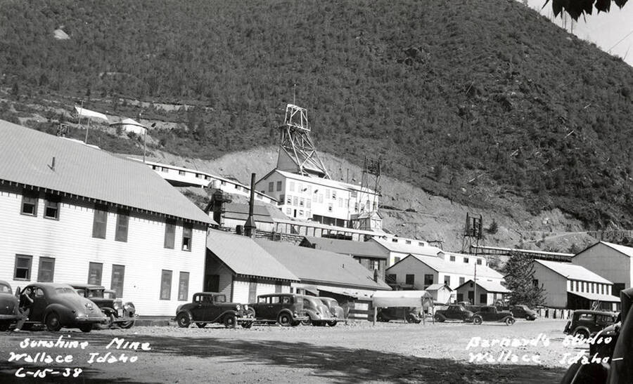 View of the Sunshine Mine in Wallace, Idaho. Cars are seen parked in front of buildings and the mountain can be seen in the background.