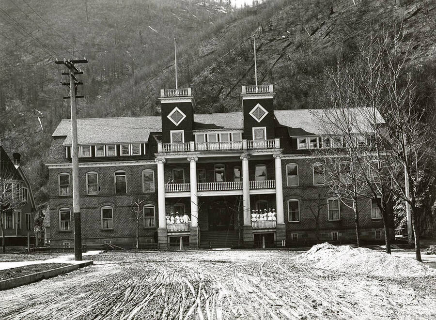 The Hospital in Wallace, Idaho, with nurses standing on the balconies and hills in the background.