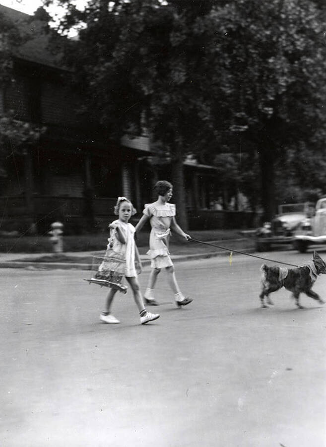 Two girls walking with their pets at the Veterans pet parade in Wallace, Idaho.