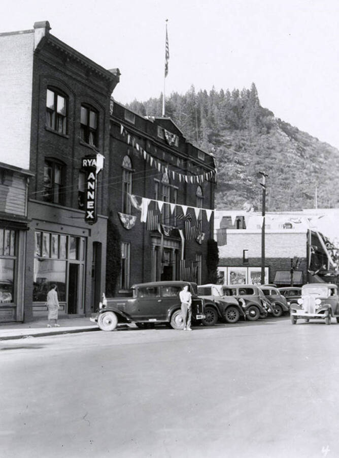 A car driving in the Elks Roundup parade in Wallace, Idaho. Cars are parked in front of buildings along the side of the street.