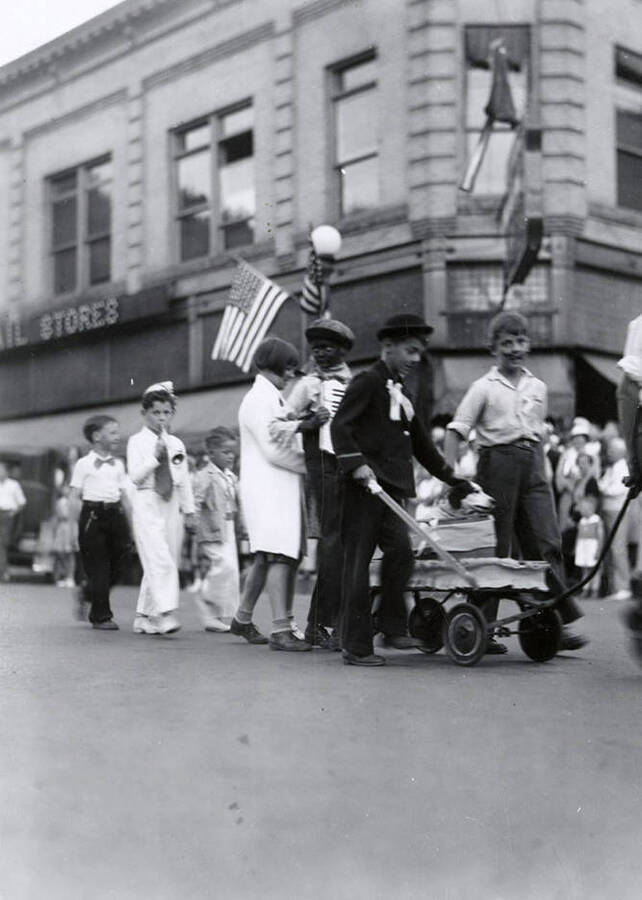 Children marching and pulling a wagon with a dog in it during the Elks Roundup parade in Wallace, Idaho.